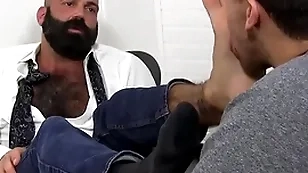 Bald bearded hunk foot worshipped and licked by young lad